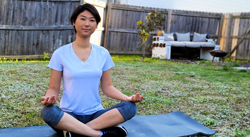 A Veteran meditating on a yoga mat in the backyard.