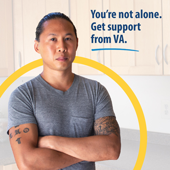 A Veteran standing in the kitchen with arms folded. The text reads, “You’re not alone. Get support from VA.”