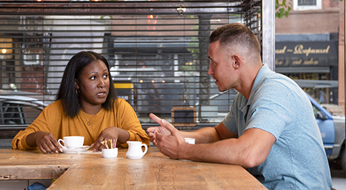 Two Veterans sitting together in a coffee shop talking.