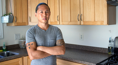 photo of a veteran standing in a kitchen looking at the camera. 