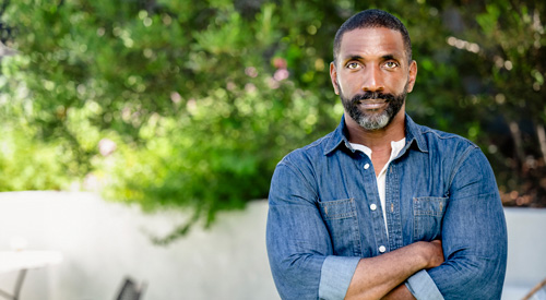 A Veteran standing in a garden and looking into the camera.