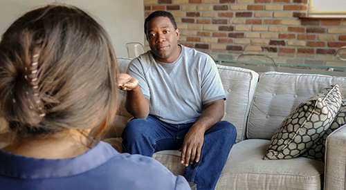 A Veteran sitting on a couch while talking to a counselor.